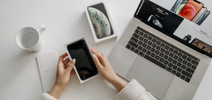 a person holding mobile phone in the box with laptop on the side